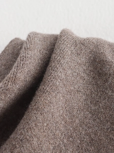 Close-up macro of soft brown knitted wool fabric texture and woven details for winter scarf