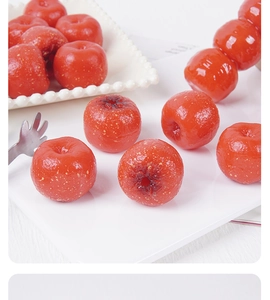 Detailed view of artificial red hawthorn fruits with glossy syrup coating on a white tray