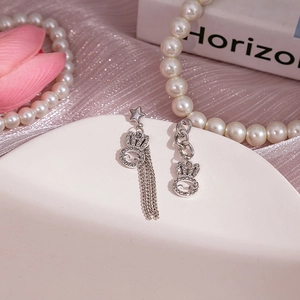Détail de boucles d'oreilles lapin asymétriques argentées avec strass, étoile et pompons