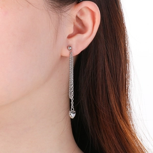 Detail of silver long tassel earrings with heart pendant on model in natural light
