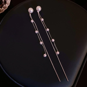 Detail of elegant faux pearl tassel earrings with silver needles on a black background