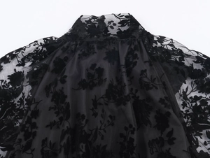 Detail of high collar with black sheer mesh and floral flocking texture on the blouse
