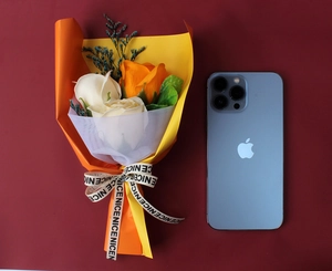 Mini soap flower bouquet with roses beside a smartphone for size reference