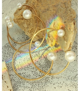 Detailed close-up of golden pearl hoop earrings resting on textured mineral stone