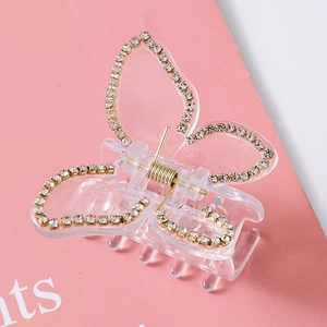 Detailed close-up of a butterfly hair claw clip with sparkling rhinestones on pink background