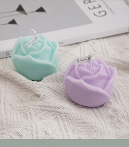 Detailed macro view of mint green and purple rose-shaped scented candles on a knit blanket