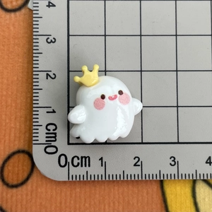 Macro shot of a 2cm cute white resin ghost charm with crown on a measuring ruler