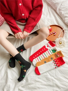 Chaussettes de Noël épaisses en polaire corail avec motifs festifs sur un lit blanc