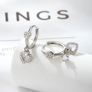 Silver heart earrings with cubic zirconia charms on minimalist white display pedestal