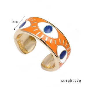 Detailed view of adjustable golden evil eye ring with orange enamel and blue eye motif
