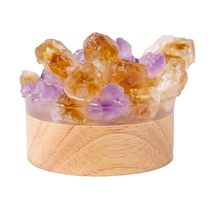 Natural purple amethyst crystal night light with round wooden base on white background