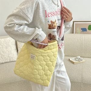 Détail du sac matelassé jaune montrant la texture, l'étiquette et l'anse tressée