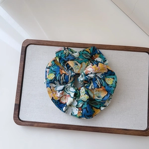 Close-up of a large floral scrunchie with colorful oil painting pattern on a wooden tray