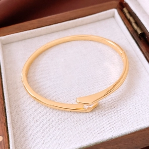 Close-up of gold plated open bangle with zircon inlay inside a wooden jewelry box
