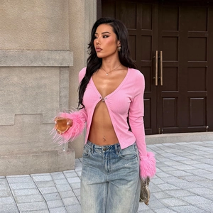 Détail du cardigan en maille côtelée rose avec poignets en plumes et décolleté en V