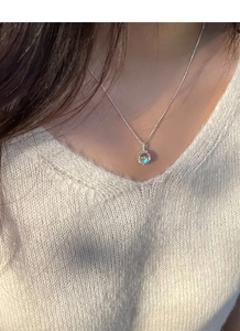 Detailed close-up of a S925 silver necklace with an iridescent round pendant on a model