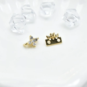 Golden flower and crown earrings with gemstones and dual-hole detail on white display