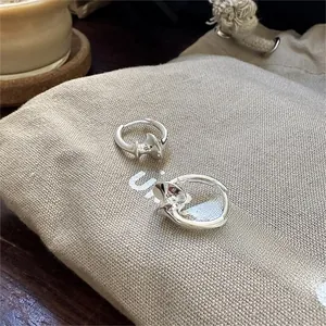 Detailed macro view of polished silver wavy hoop earrings on a beige linen pouch