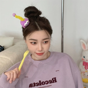 Close-up of a cute purple plush monster hair clip with big eyes on a model's hair