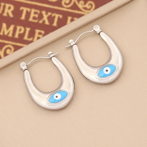 Detailed view of silver U-shaped hoop earrings with blue enamel evil eye design