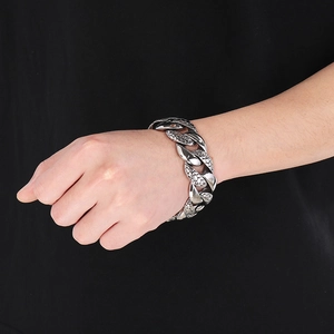 Macro detail of men's wide Cuban link bracelet with engraved pebble texture in silver finish
