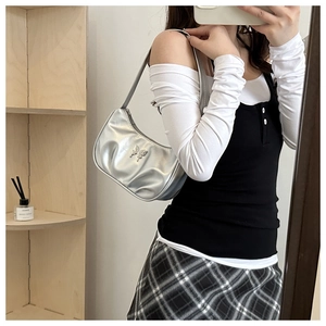 Silver pleated underarm bag featuring a metallic butterfly buckle shown on a model