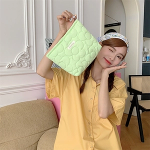 Detailed texture of green quilted floral toiletry bag with soft fabric finish