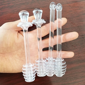 Gros plan de quatre cuillères à miel en plastique transparent sur fond de bois sombre