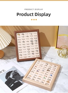 Detail of walnut wood jewelry display tray with velvet slots holding multiple gold rings