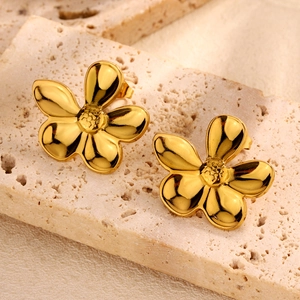 Polished gold flower stud earrings in stainless steel on a natural stone display