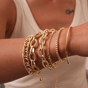 Gros plan d'un ensemble de 5 bracelets dorés avec maillons texturés et ovales superposés