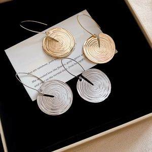 Close-up of gold and silver round earrings with spiral texture in a black jewelry box