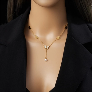 Elegant gold butterfly necklace with pearl pendant shown on a model's neck