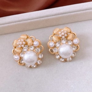 Macro shot of vintage gold flower earrings with pearls and rhinestones on beige velvet