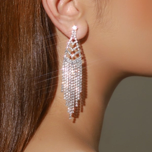 Macro close-up of sparkling rhinestone long tassel earrings worn by a model with starburst