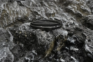Makroaufnahme eines schwarzen Lederarmbands mit Magnetverschluss auf dunklem Gestein