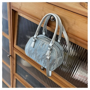 Close-up of light blue denim Boston bag with silver sequins and metallic shoulder strap
