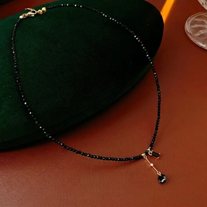 Vintage beaded necklace with black faceted stones and gold double pendants on velvet box