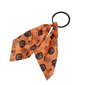 Macro detail of orange Halloween bow hair tie with black pumpkin and spider web patterns