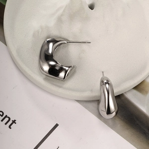 Close-up of polished silver teardrop earrings on a white textured stone display tray