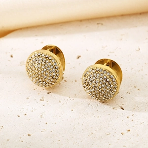 Gros plan de boucles d'oreilles ovales dorées avec zircons pavés sur fond pierre