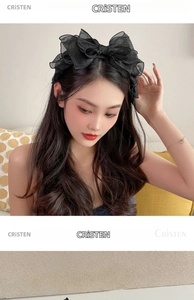 Detailed view of layered black mesh bow headband on model in a cozy indoor setting