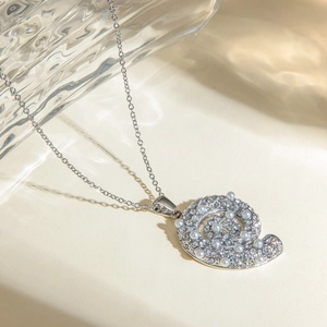 Detail van de zilveren slakkenhanger ketting met kleine parels en fonkelende strassteentjes