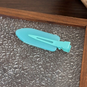 Macro di un fermaglio per capelli in acrilico verde acqua su vassoio in vetro testurizzato