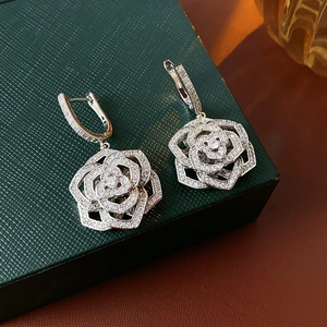 Macro detail of silver camellia flower earrings with sparkling pavé zircon stones