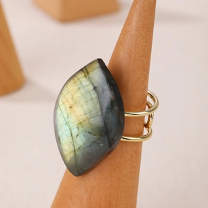 Adjustable gold ring with faceted labradorite gemstone on a wooden display stand