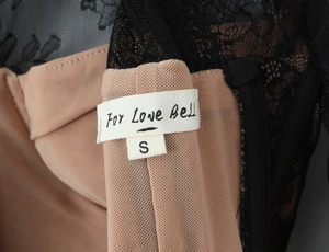 Detailed view of the brand label For Love Bell and size S on a black lace top