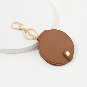 Detail of round brown PU leather keychain with gold metal clasp and mirror pocket