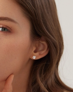 Close-up of a classic four-prong moissanite stud earring worn on a female ear lobe