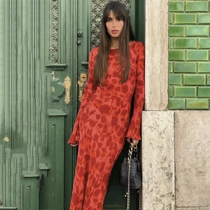 Detail of bohemian red floral print long sleeve dress on a model by a vintage green door